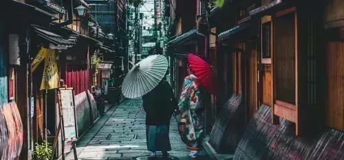 Paar, das auf Straße geht, während Regenschirm in Kyoto hält