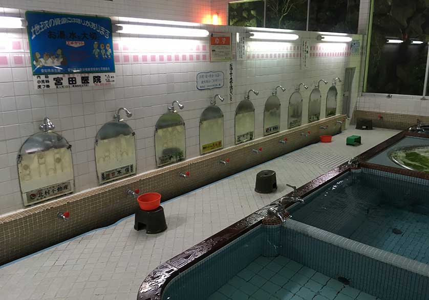 Bathhouse interior showing hot and cold taps and a shower.