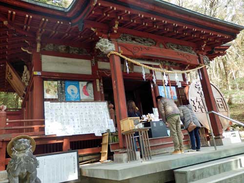 People praying at Wado Hijiri Shrine, gratuity notes to the shrine for achieving financial success to the left.