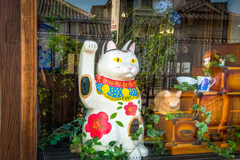 Maneki neko cat and real cat in store window, Yanaka, Tokyo, Japan.