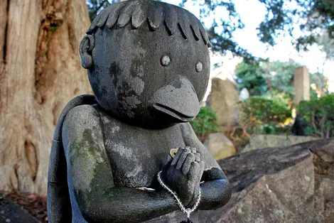 Estatua de un kappa con ofrendas colgadas.