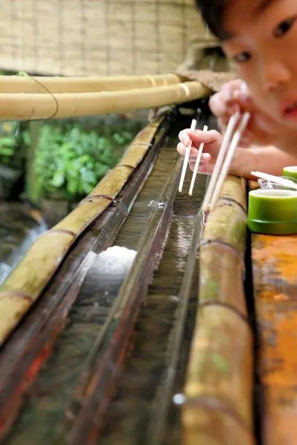 Un enfant essayant d'attraper des nagashi sômen.