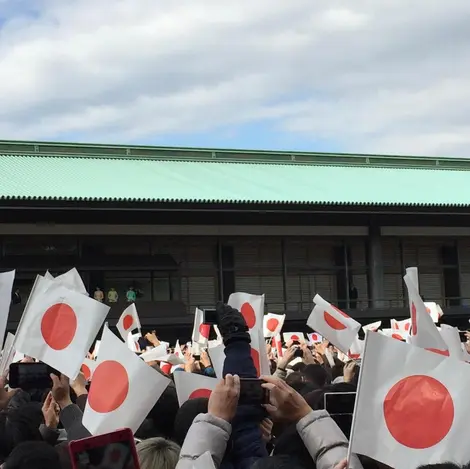 La foule du Palais Impérial agite les drapeaux et tente d'immortaliser l'instant