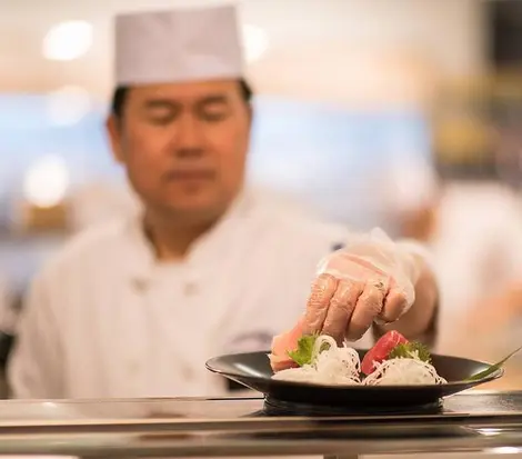 Un chef prepara un plato de sushi.