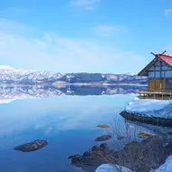 Kansaki Palace stands on Lake Tazawa & the lakeside, & beyond the lake, there’s a distant view of Mt. Akita Komagatake (Semboku City, in Akita Prefecture).