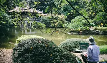 Person sitting overlooking a pond and building painting. 