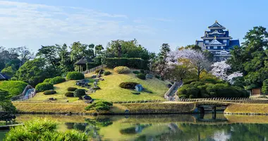 Japanese garden with large pond in the foreground and castle in the background