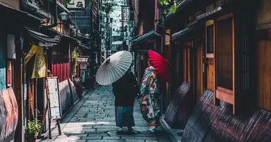 Paar, das auf Straße geht, während Regenschirm in Kyoto hält