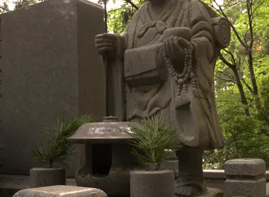 La statue d'un moine bouddhiste portant le juzu à la main