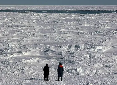 Deux hommes contemplant la mer de glace depuis la plage Deux hommes contemplant la mer de glace depuis la plage