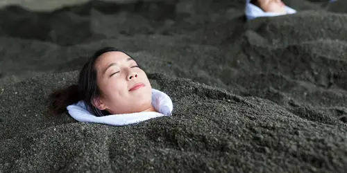 En la playa de arena negra volcánica de Beppu, puedes disfrutar de un "baño de arena" frente al mar