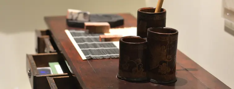 Wooden table with ink block brushes and pots. 
