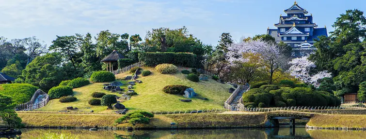 Japanese garden with large pond in the foreground and castle in the background