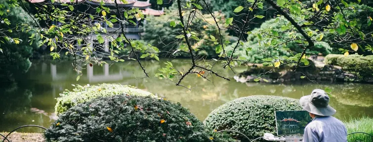 Person sitting overlooking a pond and building painting. 
