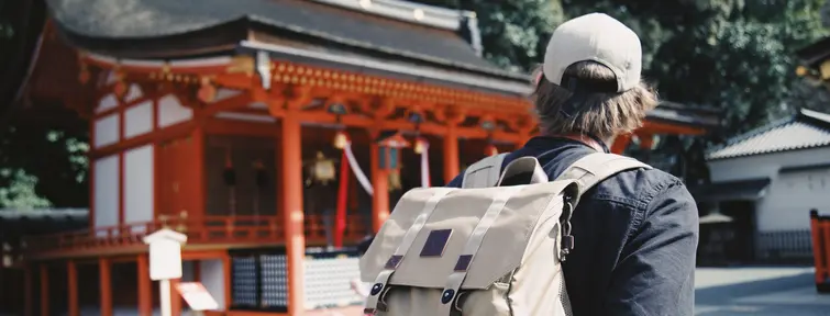 Homme avec son sac à dos devant un temple japonais